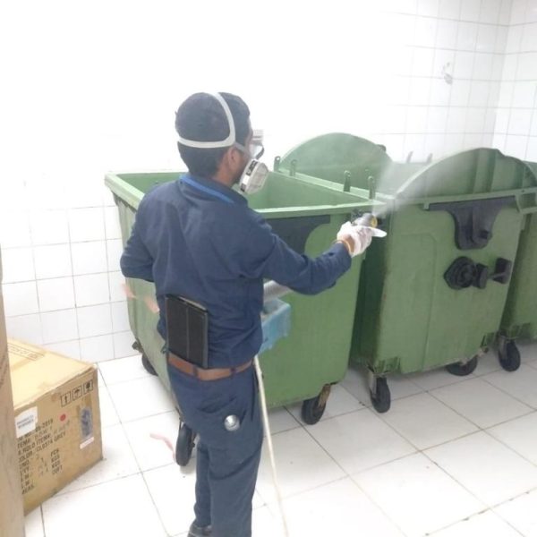 A man standing with spray gun to eradicate pest on dust bins